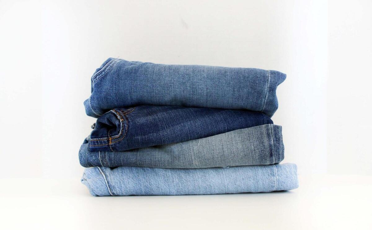 Four pairs of jeans, folded and laid out, on a table.
