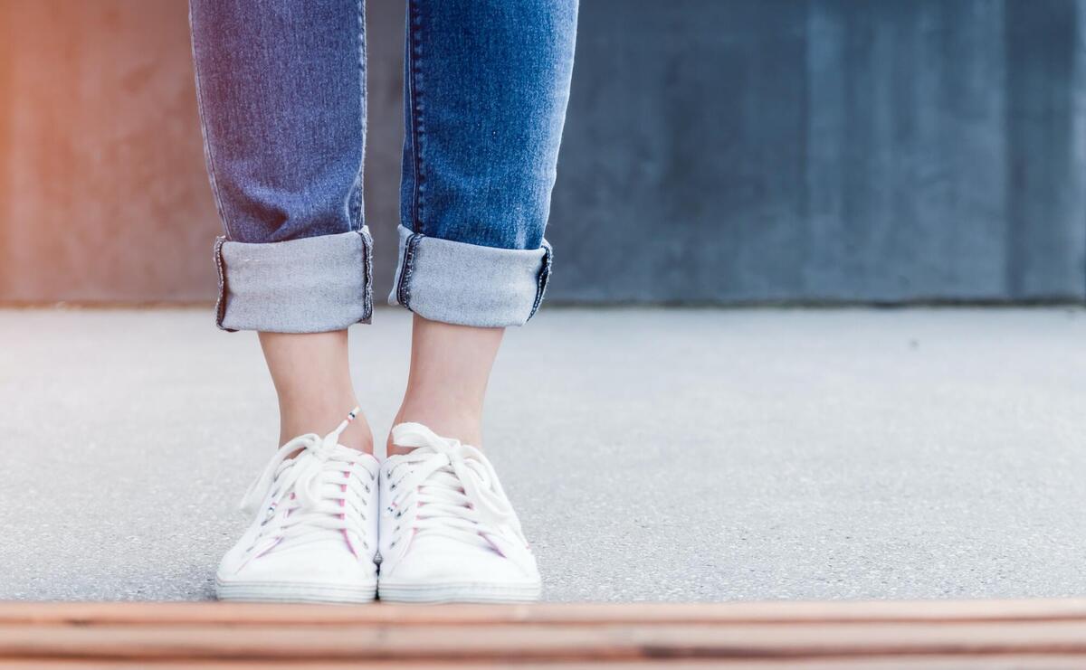 Girl wearing blue jeans and white sneakers.