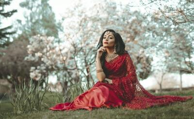 woman in red dress sitting on grass field