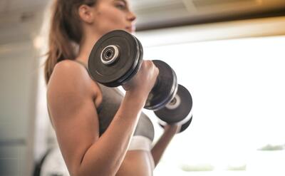A young woman is using dumbbells.