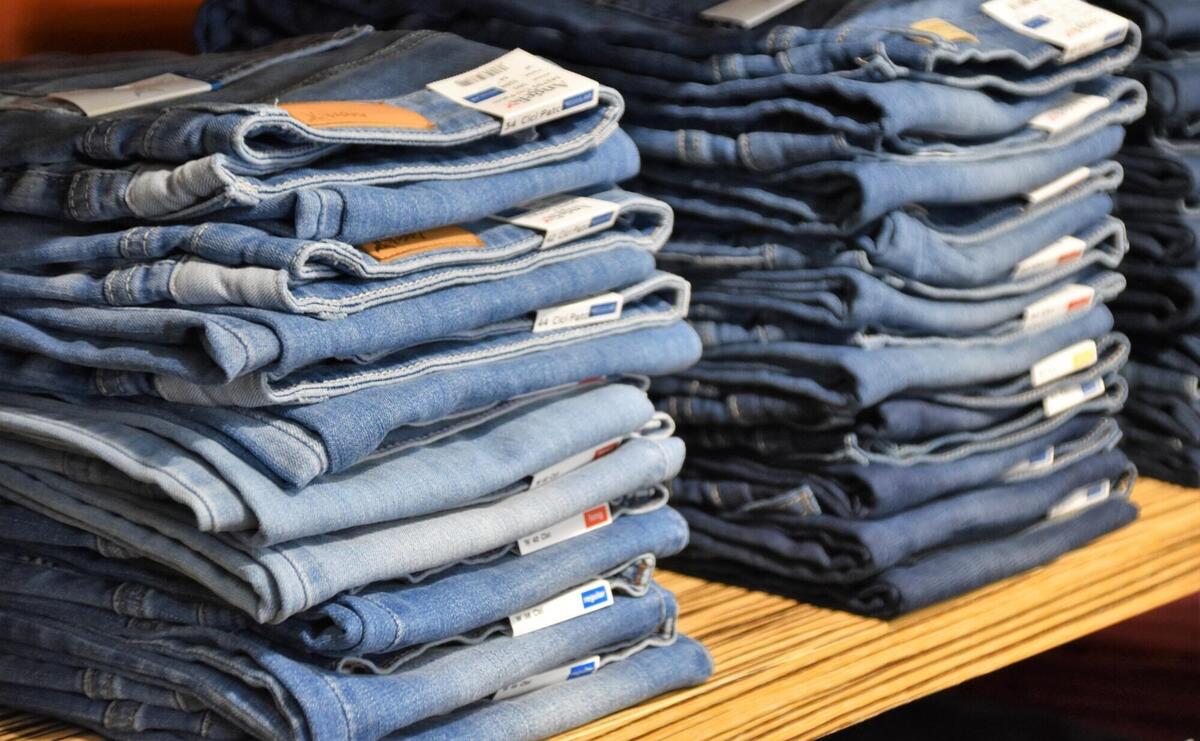 Pile of blue denim jeans on the shelf.