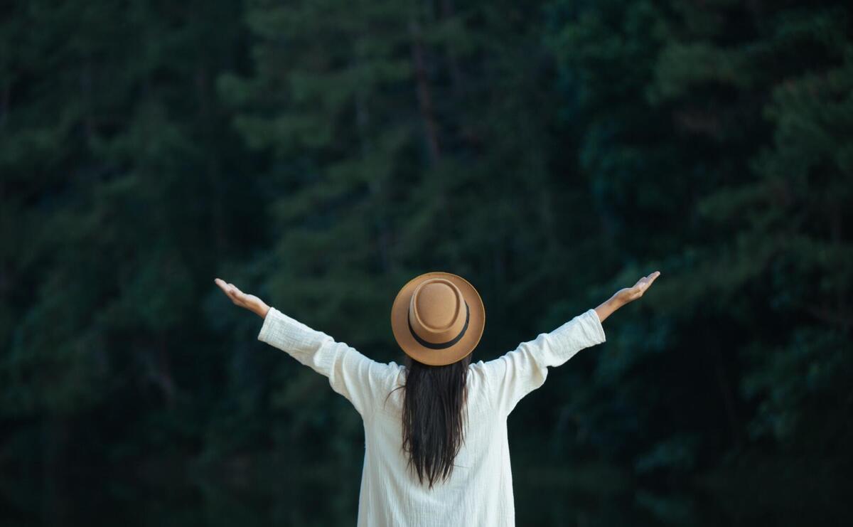 Woman with hat spread their arms and held their wings.