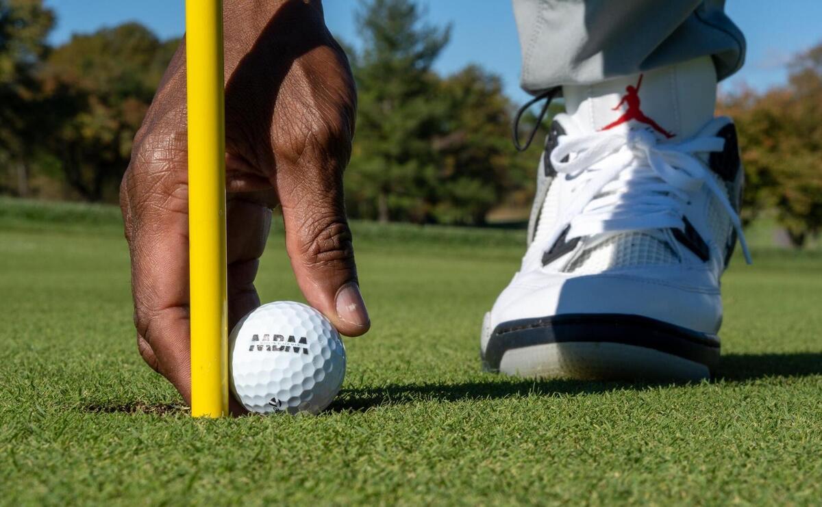 A person is placing a golf ball on the ground.