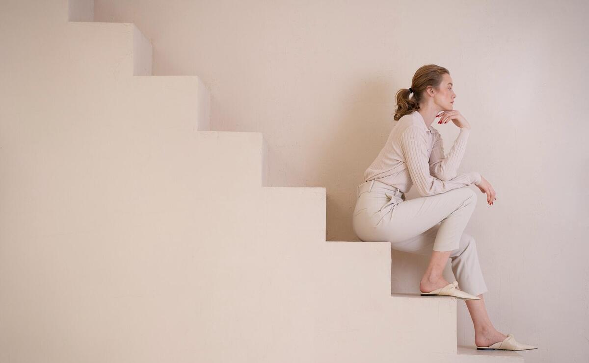 Beautiful woman wearing a minimalist shirt and sitting on the stairs.