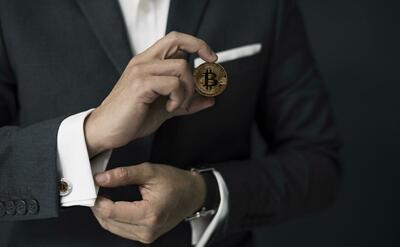 A businessman in suit holding a bitcoin.