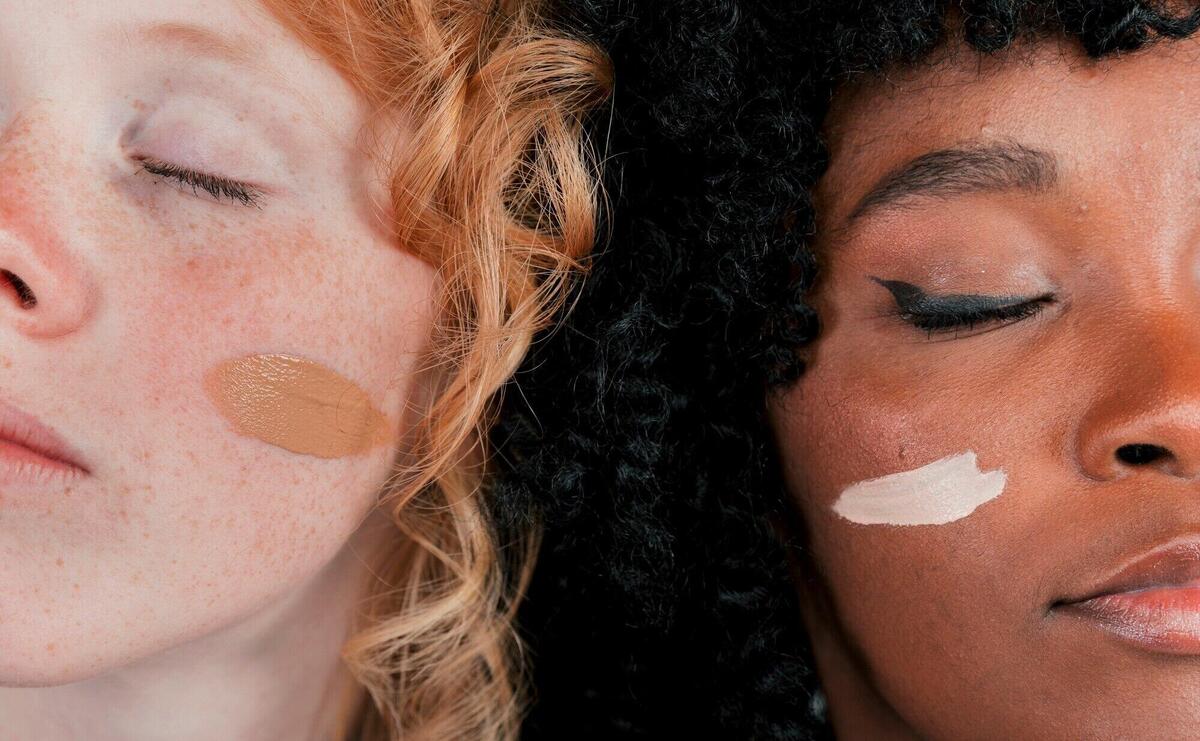 Close-up of an african and caucasian woman's face with skin tone foundation cream