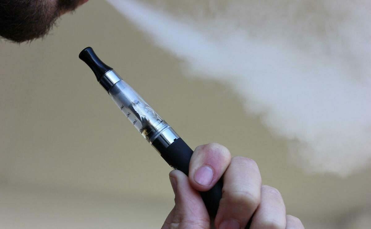 A person is blowing out smoke with his electronic cigarette.