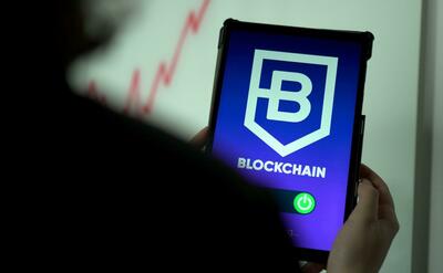 A person is holding a mobile device with a blockchain application.