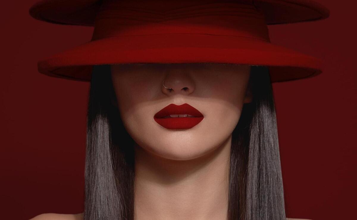 No recognizible model with half of a face covered by red hats and wear a strong matte red lipstick red background image about red lips