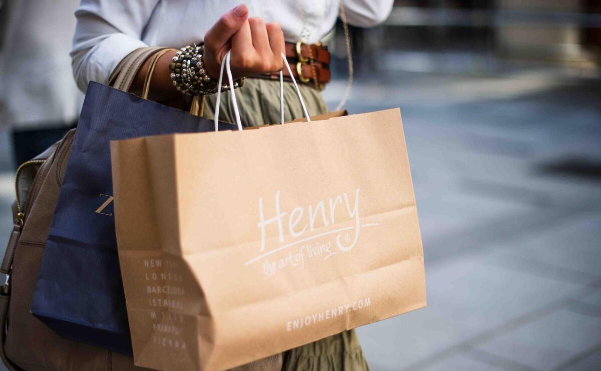 Woman holding a light brown shopping bag in her hand.