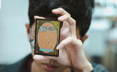 A boy is holding a Magic: The Gathering card.