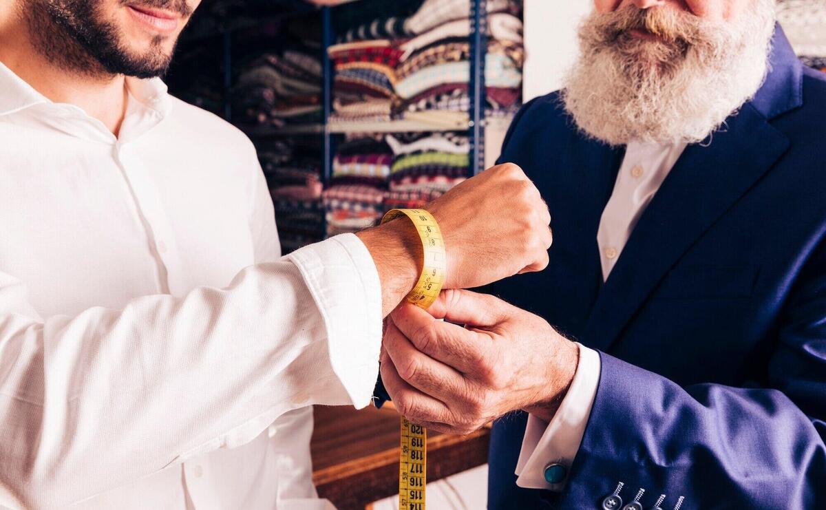 Close-up of a fashion designer taking measurement of his customer's wrist