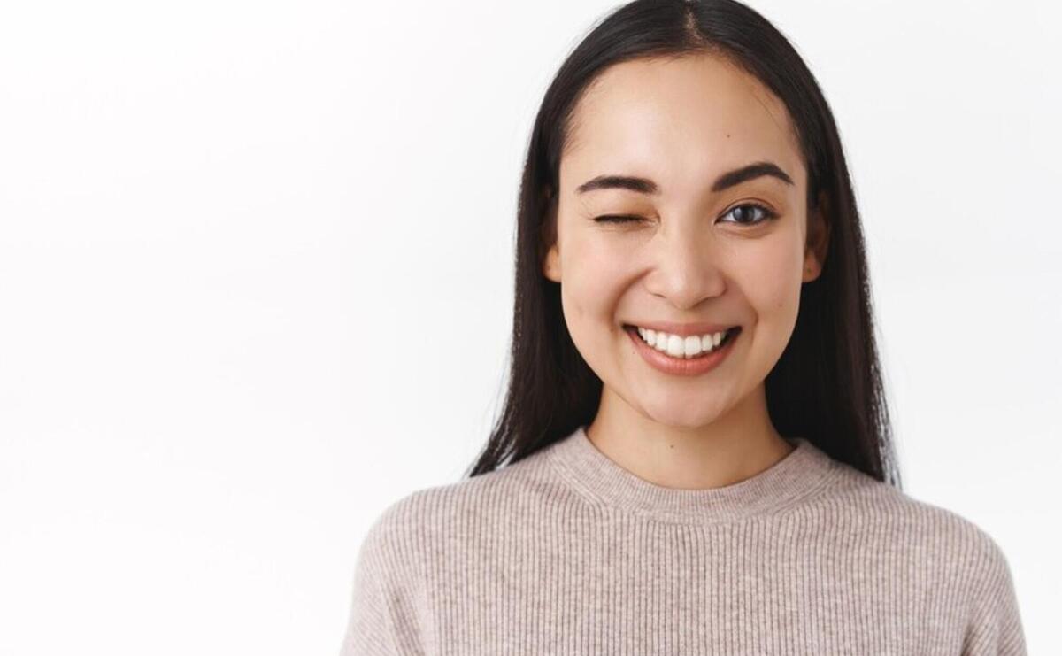 Close-up sassy, enthusiastic happy smiling asian woman with long dark hair, natural nude make-up, having great day, send positive vibes, winking to cheer friend up and say everything under control