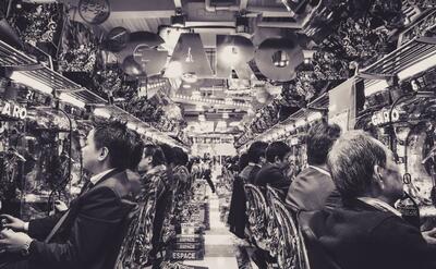 Lot of people are sitting inside a Japanese Pachinko.