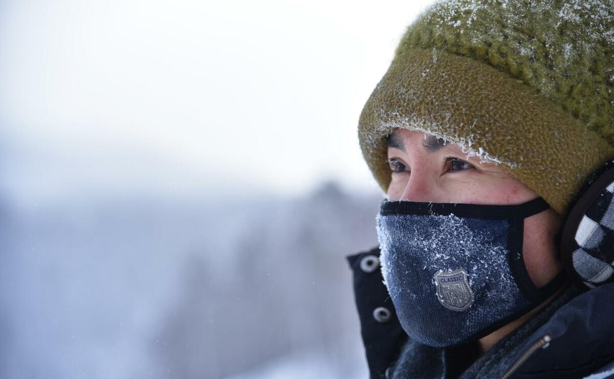 Woman wearing green knit cap and blue mask.