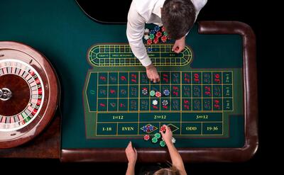 Man croupier and woman playing roulette at the table in the casino. top view at a roulette green table with a tape measure.